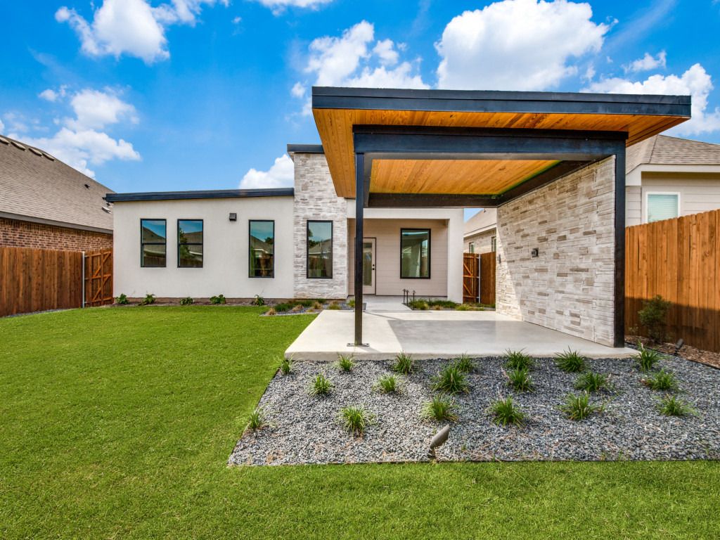 Covered back patio with wood ceiling overlooking a green lawn